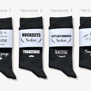 May include: Four pairs of black socks with white bands. The socks have various phrases, including "Will you be my groomsman?" and "Let's get married." One pair is personalised with "For Marcel."