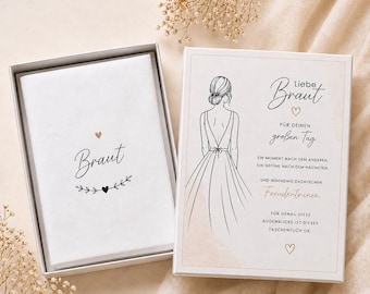 May include: A white gift box with a lid, containing a card with the word "Braut" and a heart design. The open box reveals a card with a bride illustration and German text. The overall theme is wedding-related.