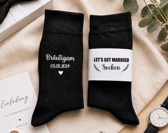 May include: Black socks with white text reading "Bräutigam 03.08.2024" and a heart, and "LET'S GET MARRIED Socken". Wedding-themed, with a bow tie, invitation, rings, and watch. A perfect gift for the groom.
