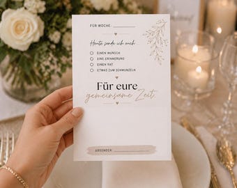 May include: A white card with German text, held by a hand, with a floral design. The card includes fill-in-the-blank sections for a week, a sender, and options for a wish, memory, advice, or something to smile about.