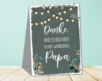 May include: A gray card with a white border and a message that reads "Danke. Dass es dich gibt! Du bist wundervoll Papa." The card is decorated with a string of lights and floral accents.