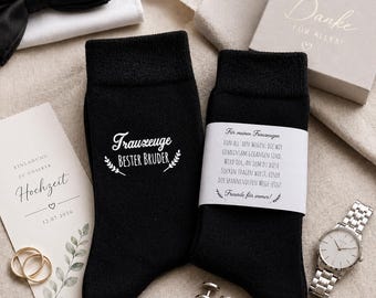 May include: Black socks with white text reading "Trauzeuge Bester Bruder" and a second pair with a white label. A wedding invitation, rings, a watch, cufflinks, and a bow tie are also visible.