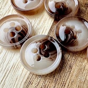 May include: A set of six brown and white swirl patterned buttons with four holes each. The buttons are made of a smooth, shiny material.