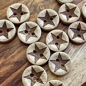 May include: A collection of brown and beige wooden buttons with a five-pointed star design. The stars are a darker brown color and have two holes in the center.