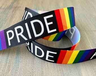 May include: Black ribbon with the word "PRIDE" printed in white letters. The ribbon is decorated with a rainbow stripe pattern.