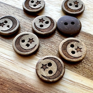 May include: Eight wooden buttons with a crescent moon and star design. The buttons are brown and have two holes each.