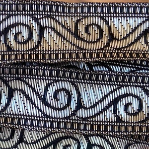 May include: Black and gold trim with a repeating pattern of stylized waves and swirls. The trim is woven and has a textured surface.