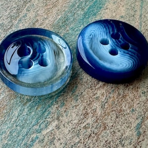 May include: Two blue and white swirl patterned plastic buttons with three holes each.