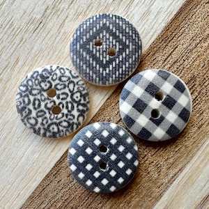 May include: Four black and white patterned buttons with two holes each. The buttons are made of wood and have a variety of patterns, including gingham, leopard print, and geometric designs.