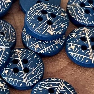 May include: A collection of navy blue buttons with a white geometric design. The buttons are round with either two or four holes. The buttons are made of wood and are suitable for sewing projects.