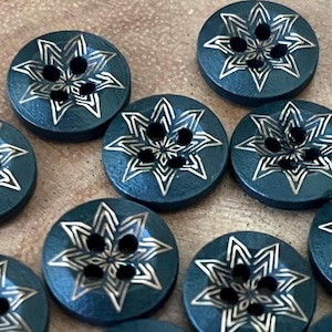 May include: A collection of dark teal wooden buttons with a starburst design. Each button features a metallic gold-colored starburst pattern and four holes for sewing. These decorative buttons are ideal for sewing and craft projects.