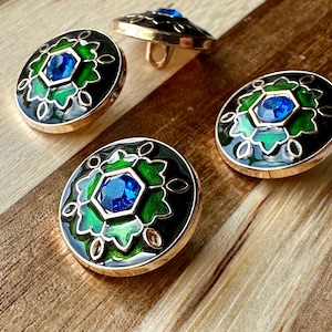 May include: Three round, gold-toned buttons with a black background and green enamel design. Each button features a blue rhinestone in the center.