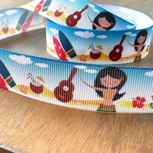 May include: White ribbon with a blue and white repeating pattern of a hula dancer, a surfboard, a coconut drink, a ukulele, and clouds. The ribbon is on a wooden surface.