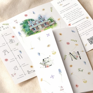 Puede incluir: Juego de papelería de boda con una invitación tríptica con detalles florales y una ilustración en acuarela de una casa. La invitación incluye el orden del día, detalles y un código QR.