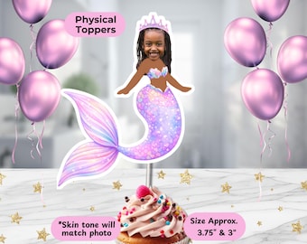 May include: A custom cupcake topper featuring a cutout of a child with a mermaid tail, wearing a pink crown. The topper is placed in a cupcake with pink frosting and sprinkles. Text includes Physical Toppers, Size Approx. 3.75" & 3", and *Skin tone will match photo.