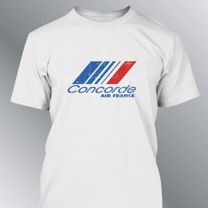 Könnte beinhalten: Weißes T-Shirt mit dem Concorde Air France Logo. Das Logo zeigt blaue und rote schräge Streifen mit dem Wort "Concorde" in Blau und "AIR FRANCE" darunter. Das Design hat einen Used-Look.