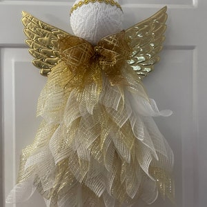 May include: A white angel Christmas decoration with gold wings and a gold bow. The angel is made of mesh and has a white lace ball head.