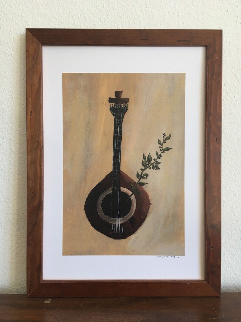 May include: A framed print of a painting depicting a dark brown guitar with a green plant growing out of the sound hole. The background is a light yellow-brown color. The artist's signature is visible in the bottom right corner.