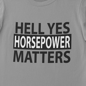 以下が含まれることがあります： 黒い文字で「HELL YES HORSEPOWER MATTERS」とプリントされた灰色のTシャツです。
