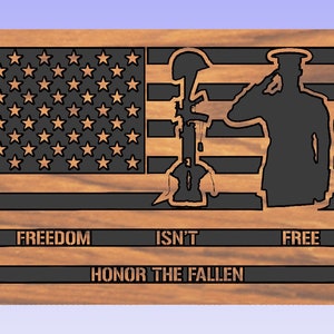 May include: A wooden sign with a black silhouette of a soldier saluting in front of an American flag. The text "FREEDOM ISN'T FREE" is written below the flag, and the text "HONOR THE FALLEN" is written below that.