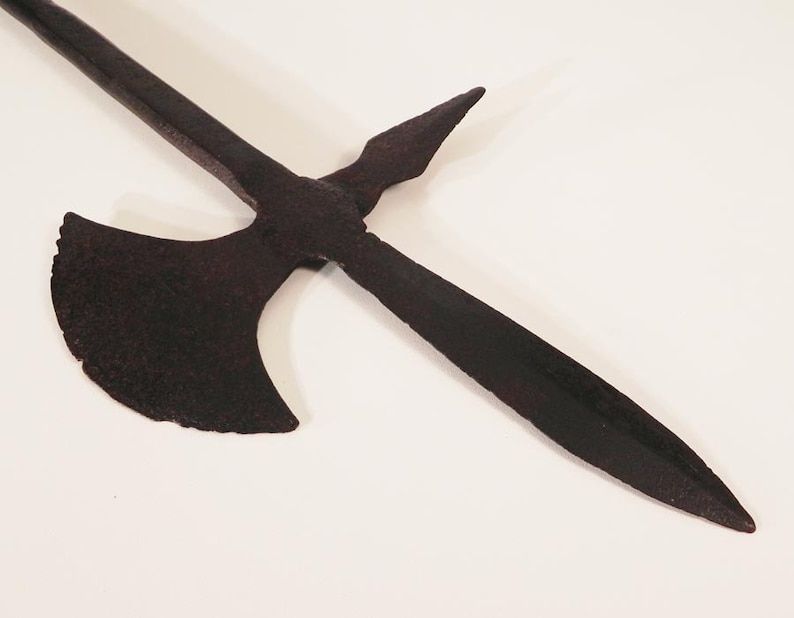 May include: A black metal weapon with a long, pointed blade and a crescent-shaped axe head. The weapon is made of iron and has a rustic, aged appearance.
