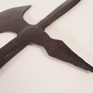 May include: A rusty, medieval-style weapon with a double-headed axe and a spear point. The weapon is made of metal and has a dark brown color.