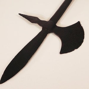 May include: A black metal weapon with a long, pointed blade and a curved axe head. The weapon is made of metal and has a rustic, aged appearance.