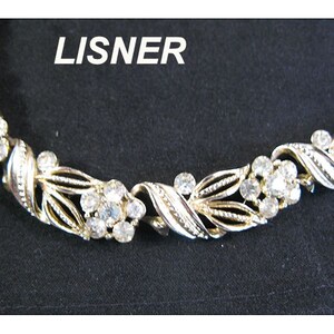 Könnte beinhalten: Ein silberfarbenes Armband mit einem filigranen Design aus Blättern und klaren Strasssteinen. Das Armband ist mit "LISNER" gekennzeichnet.