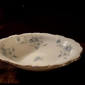 May include: White oval serving bowl with a scalloped edge and a gold rim. The bowl is decorated with a delicate blue floral pattern. A classic piece for serving salads or side dishes.