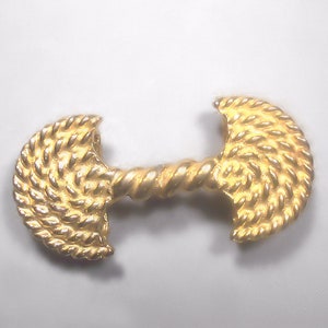 Peut inclure: Un fermoir en métal doré avec un motif en forme de corde. Le fermoir est composé de deux demi-cercles reliés par un motif de corde torsadée.