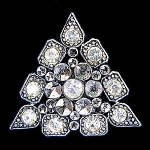 May include: A silver triangular brooch with a geometric design featuring clear rhinestones.