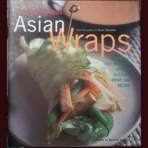 May include: A cookbook titled "Asian Wraps" by Nina Simonds, featuring a colorful image of a lettuce wrap filled with vegetables and tofu. The book cover includes the text "from the author of Asian Noodles" and "Easy, Healthy Buns to Stuff, Wrap, and Relish."