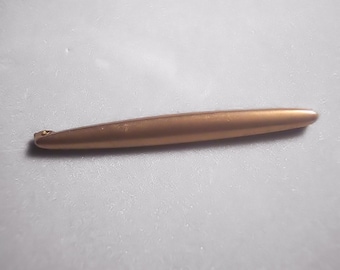 May include: A gold-colored metal pen with a rounded tip.