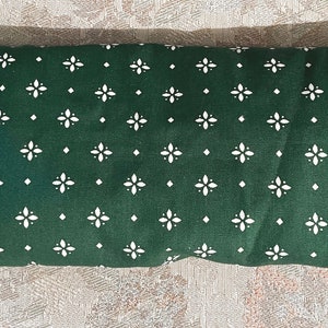May include: A green fabric pillow with a white diamond pattern. The pillow is folded in half and has a soft, textured surface.