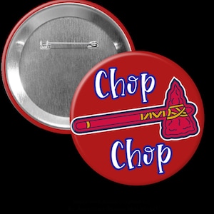 Puede incluir: Un botón rojo con las palabras "Chop Chop" en escritura blanca y un gráfico de tomahawk. El tomahawk es rojo, amarillo y azul. El botón tiene un respaldo de alfiler plateado.