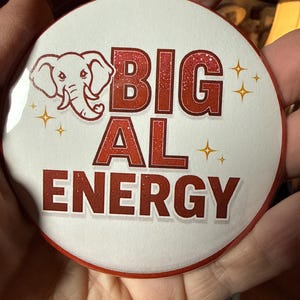 Könnte beinhalten: Ein runder, weißer Button mit dem Text "BIG AL ENERGY" in roten Buchstaben. Auf der linken Seite befindet sich eine Elefanten-Grafik. Der Button hat einen roten Rand und vier goldene Sternchen.
