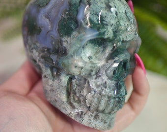 May include: A green and white agate skull with intricate details. The skull is carved from a natural stone and has a unique, organic look.