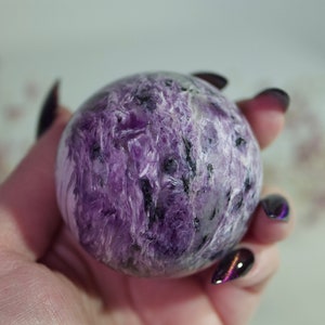 May include: A purple and black sphere of polished amethyst crystal. The crystal has a swirling, layered pattern.