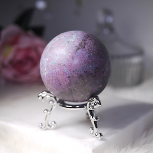 May include: A purple and blue sphere with a sparkly finish sits on a silver stand. The sphere is a decorative object.
