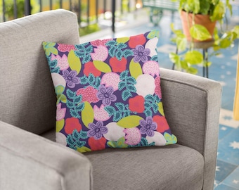 Puede incluir: Un sillón gris con un cojín con estampado floral. El cojín presenta flores rosas, verdes, blancas y azules sobre un fondo azul oscuro.