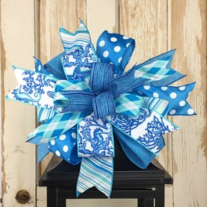 May include: A blue and white bow with a seahorse pattern, polka dots, and stripes. The bow is tied on top of a black lantern.