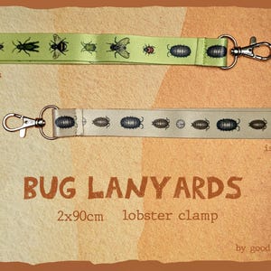 May include: Two bug-themed lanyards with lobster claw clasps. One is light green with various bug illustrations, the other is off-white with isopod designs. The text "BUG LANYARDS" is displayed.