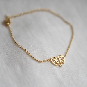 Peut inclure: Un bracelet en chaîne dorée avec un délicat pendentif en forme d'éléphant. L'éléphant est réalisé dans un design géométrique.