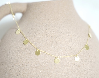 May include: A gold chain necklace with small, round, gold charms hanging from it.