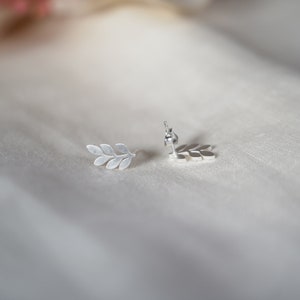 May include: A pair of silver leaf earrings. The earrings are in the shape of a branch with multiple leaves.