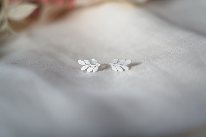 May include: A pair of silver leaf earrings. The earrings are small and delicate, and they are perfect for adding a touch of elegance to any outfit.