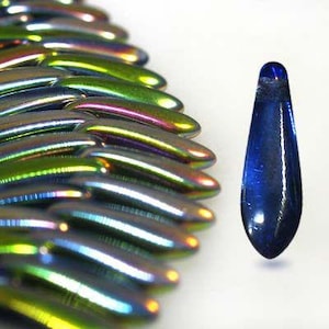 May include: A close-up of a teardrop-shaped glass bead with a deep blue iridescent finish. The bead is surrounded by a fan of iridescent glass beads in shades of green, blue, and purple.