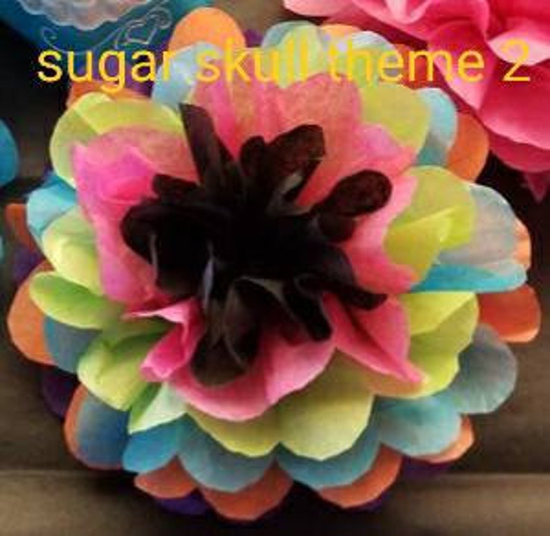 May include: A colorful, layered paper flower with a black center. The petals are a mix of pink, orange, yellow, green, and blue. The text "sugar skull theme 2" is visible in the upper left corner.