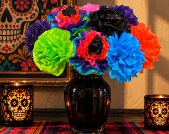 Può includere: Un bouquet di fiori in carta velina dai colori vivaci, tra cui verde neon, blu brillante, arancione, viola, rosa e nero, sistemato in un vaso di vetro nero lucido. I fiori presentano petali increspati e stratificati.