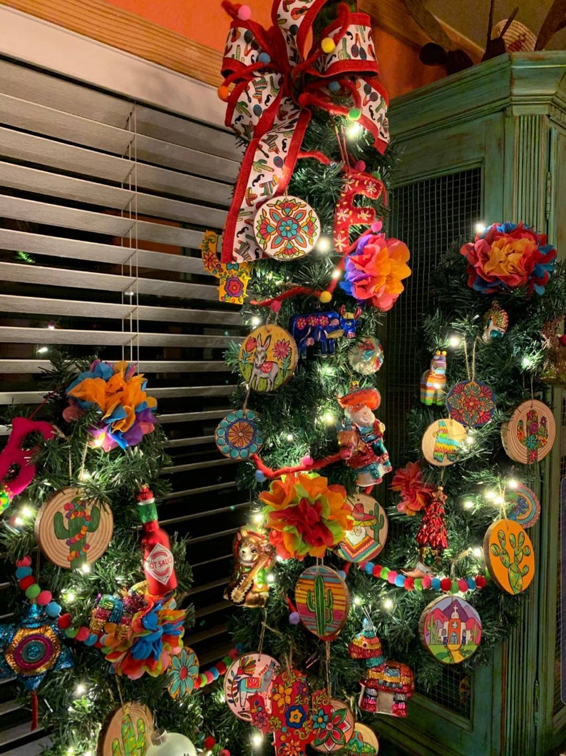 Pu&ograve; includere: Un albero di Natale decorato con ornamenti colorati, tra cui cactus, sombreros e disegni floreali. L'albero &egrave; adornato con luci a stringa e un grande fiocco rosso con un nastro fantasia. Il tema generale &egrave; una celebrazione vibrante.